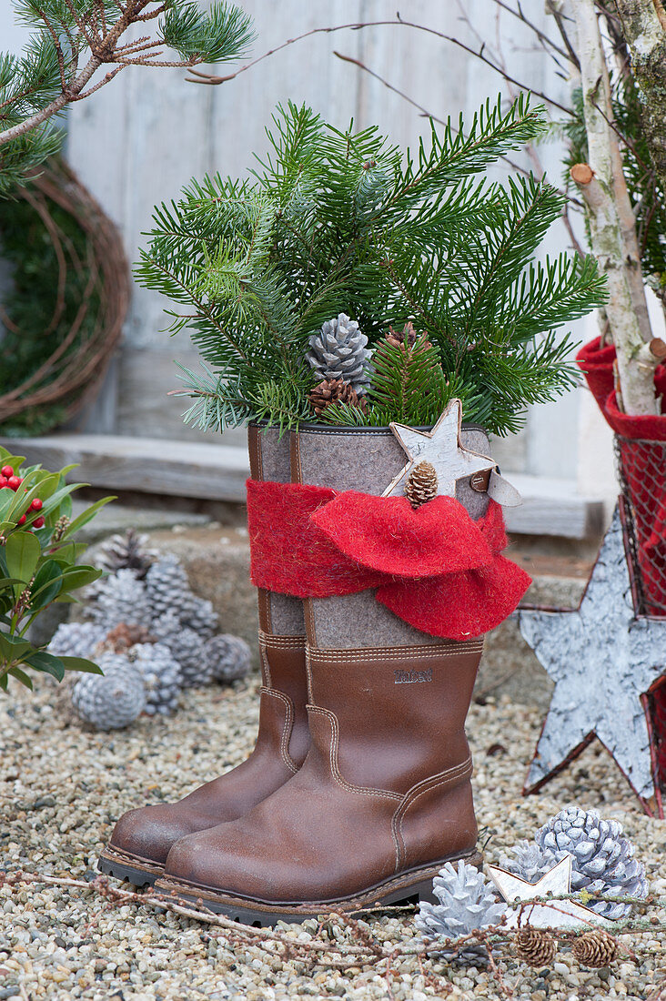 Boots with fir branches, star, cones and red felt ribbon for Santa Claus