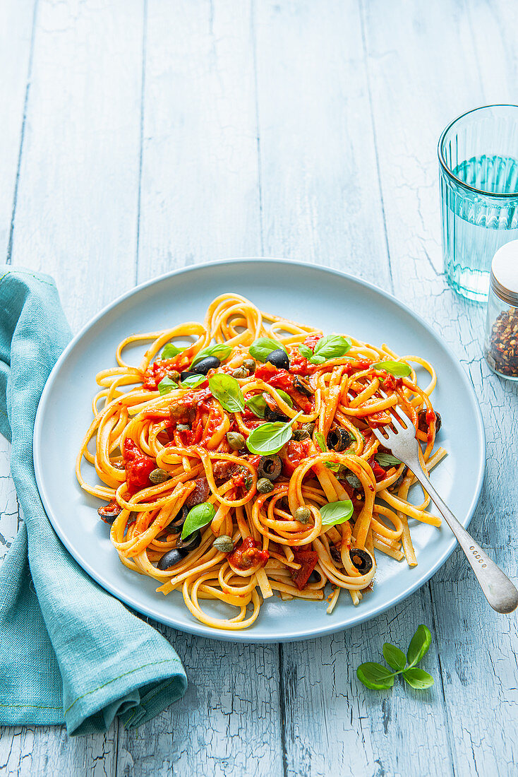Spaghetti Puttanesca mit Oliven, Kapern, Tomaten, Chiliflocken und frischem Basilikum