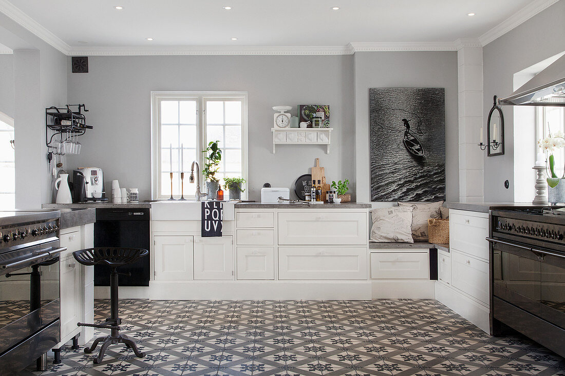 Großzügige Landhausküche in Schwarz, Weiß und Grau mit dekorativem Ornamentfliesenboden