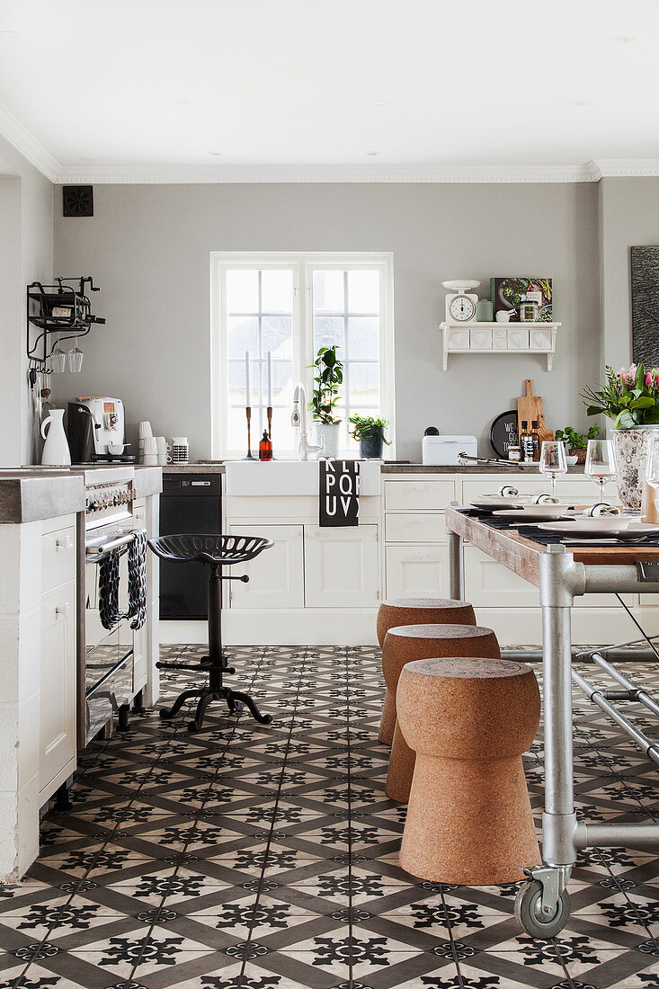 Vintage-Esstisch und Korkhocker in Landhausküche mit dekorativem Ornamentfliesenboden