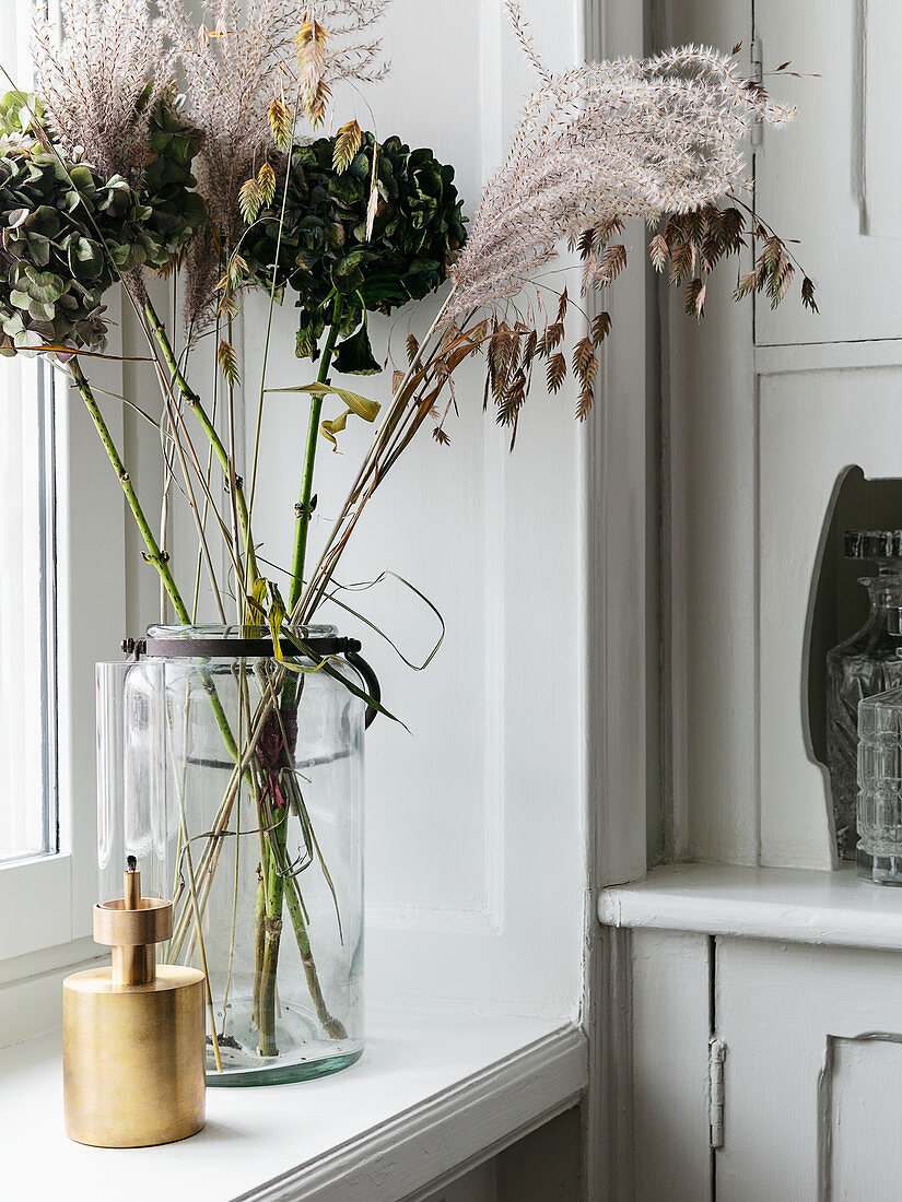 Dried flowers in vase on windowsill