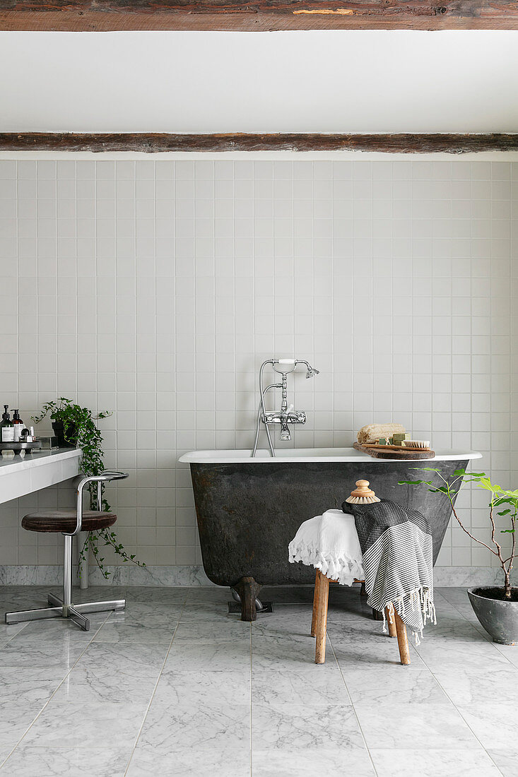 Kleine freistehende Badewanne im schlichten Bad in Grau und Weiß