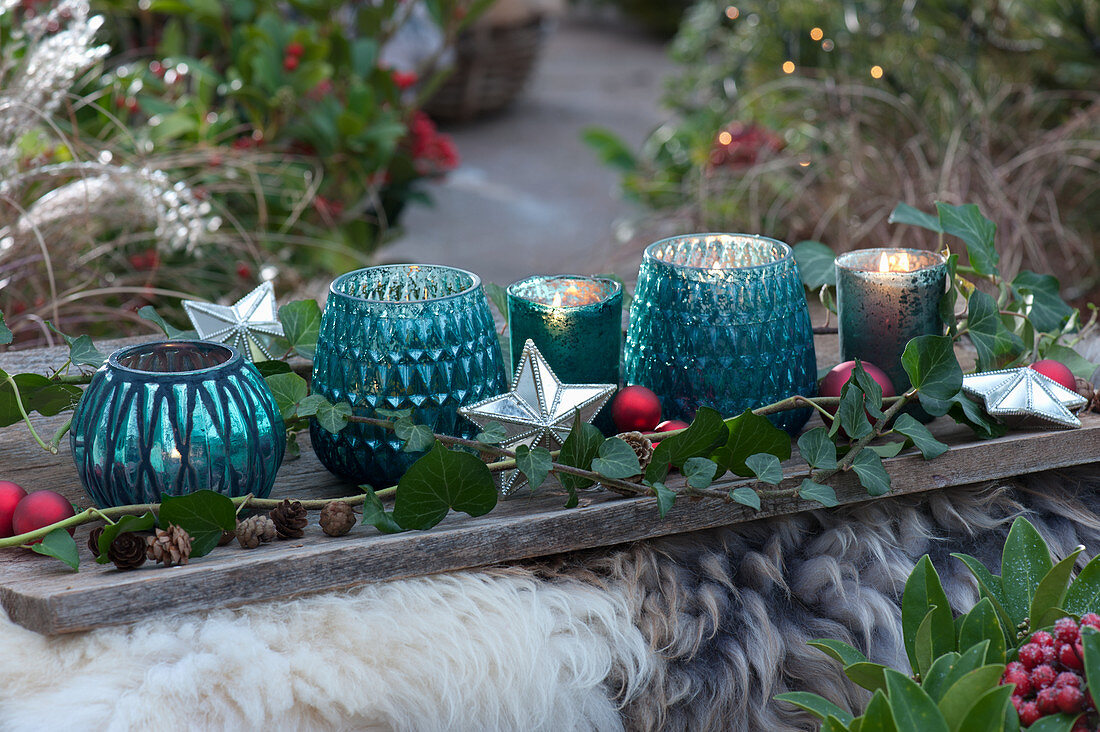 Turquoise lanterns with ivy tendrils, stars and balls on a wooden board