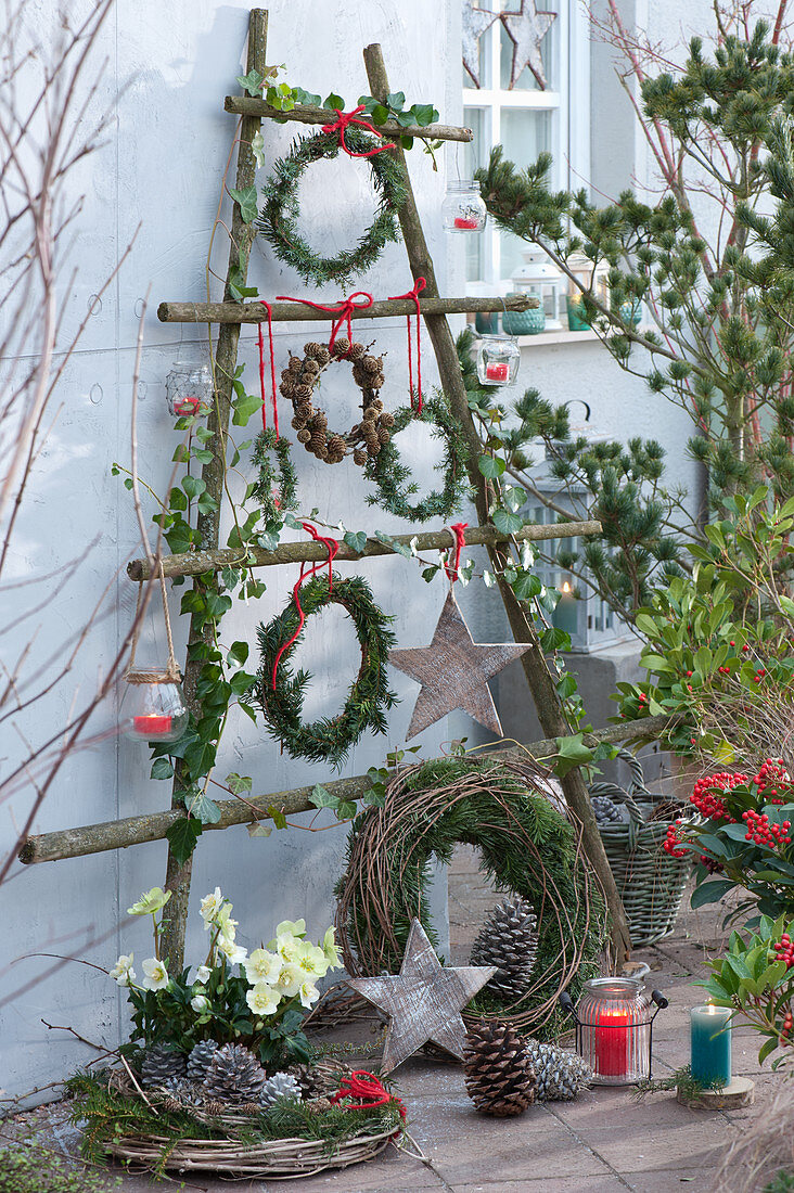 Weihnachtlich dekorierte Terrasse mit Kränzen, Sternen, Zapfen und Lichtern an selbstgebautem Gestell aus Ästen