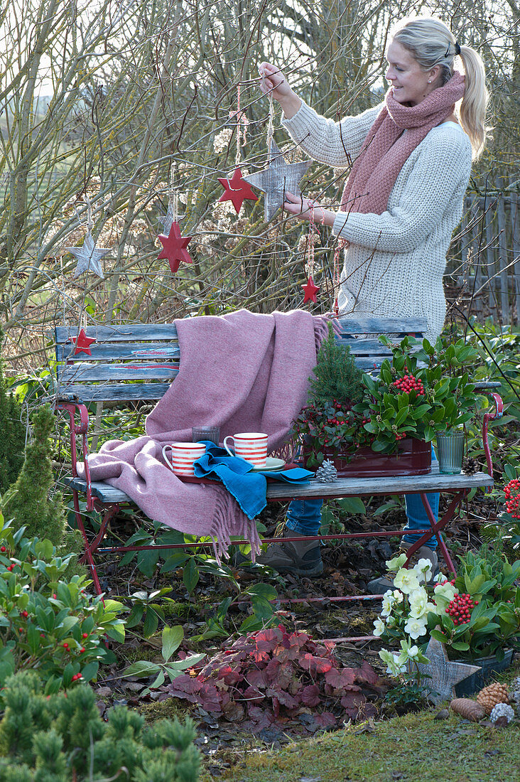 Frau dekoriert Sitzplatz im Garten weihnachtlich mit Holzsternen