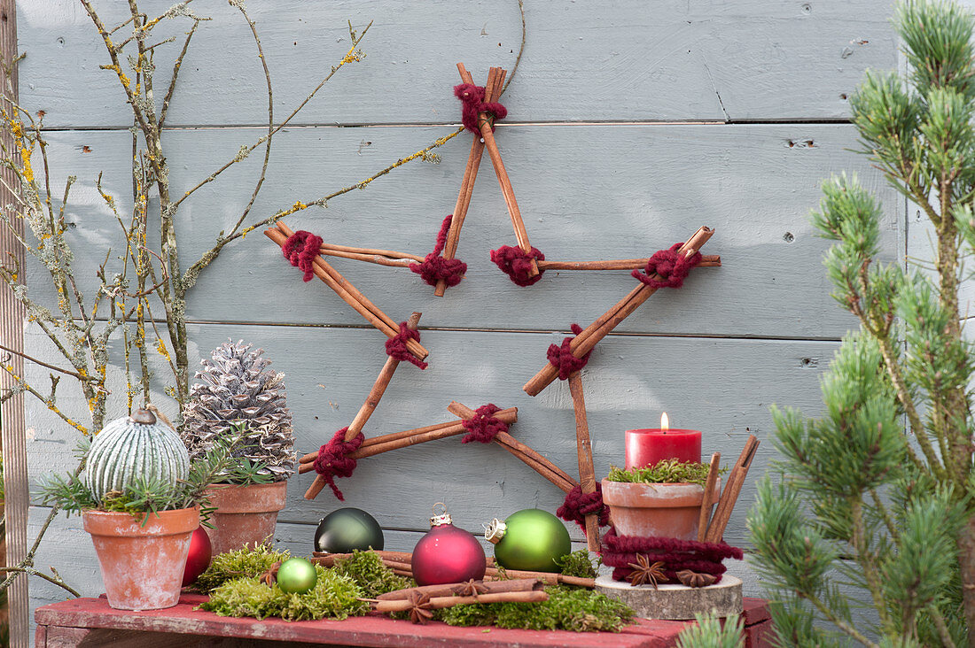 Star made of cinnamon sticks with balls, cones and candles as a Christmas decoration