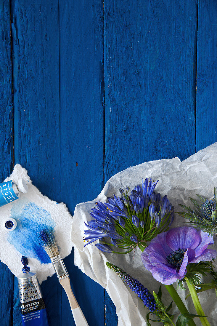 Anemone, agapanthus, veronica and sea holly on blue boards