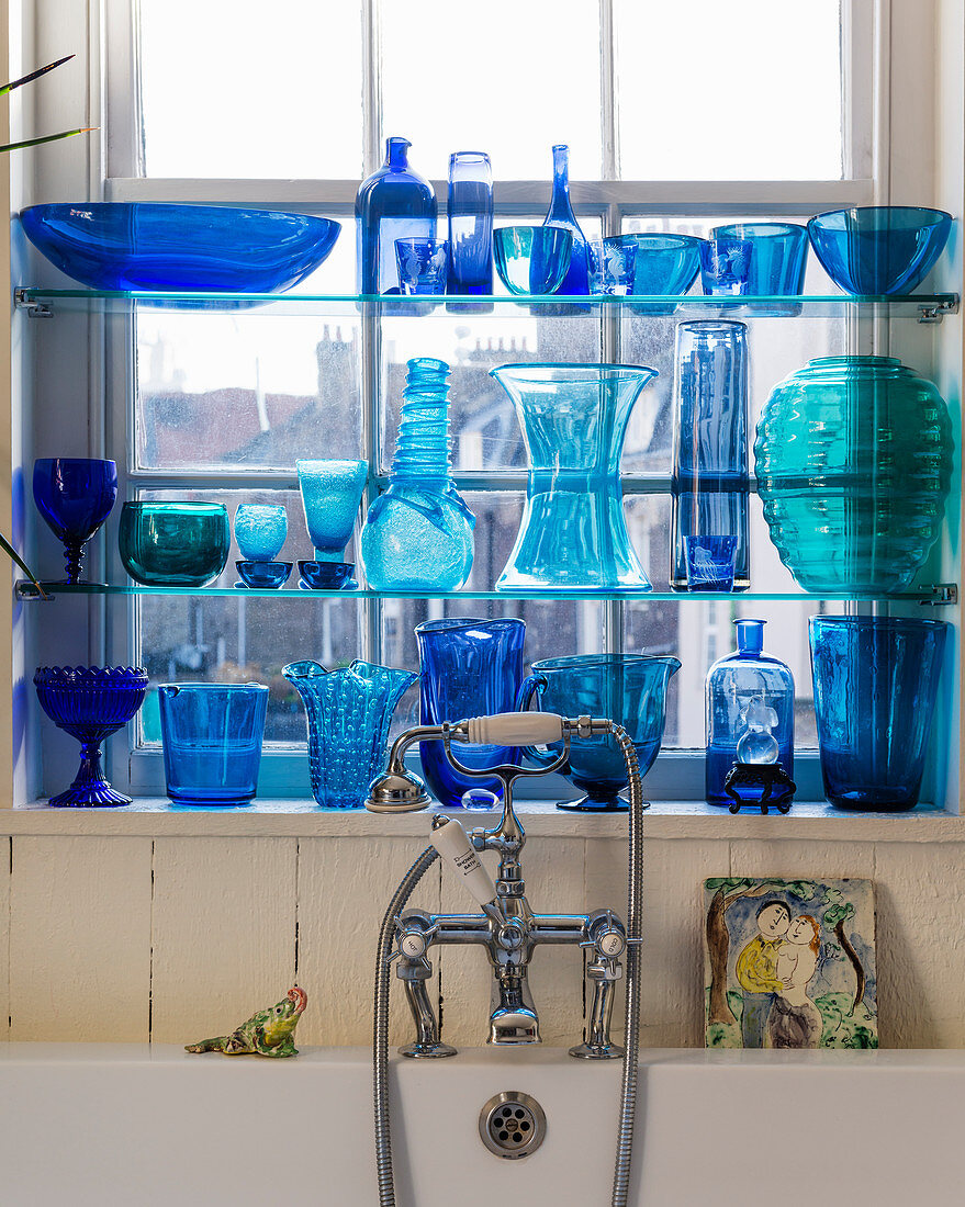 Blaue Glasvasen und Flaschen auf Regalen am Fenster