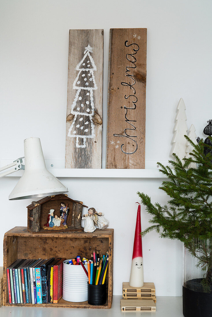 Weihnachtsbilder auf Holzbrettern, darunter Weihnachtskrippe auf Holzkiste