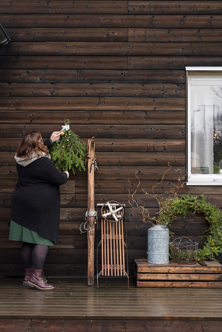Woman hanging Christmas decorations on wooden wall
