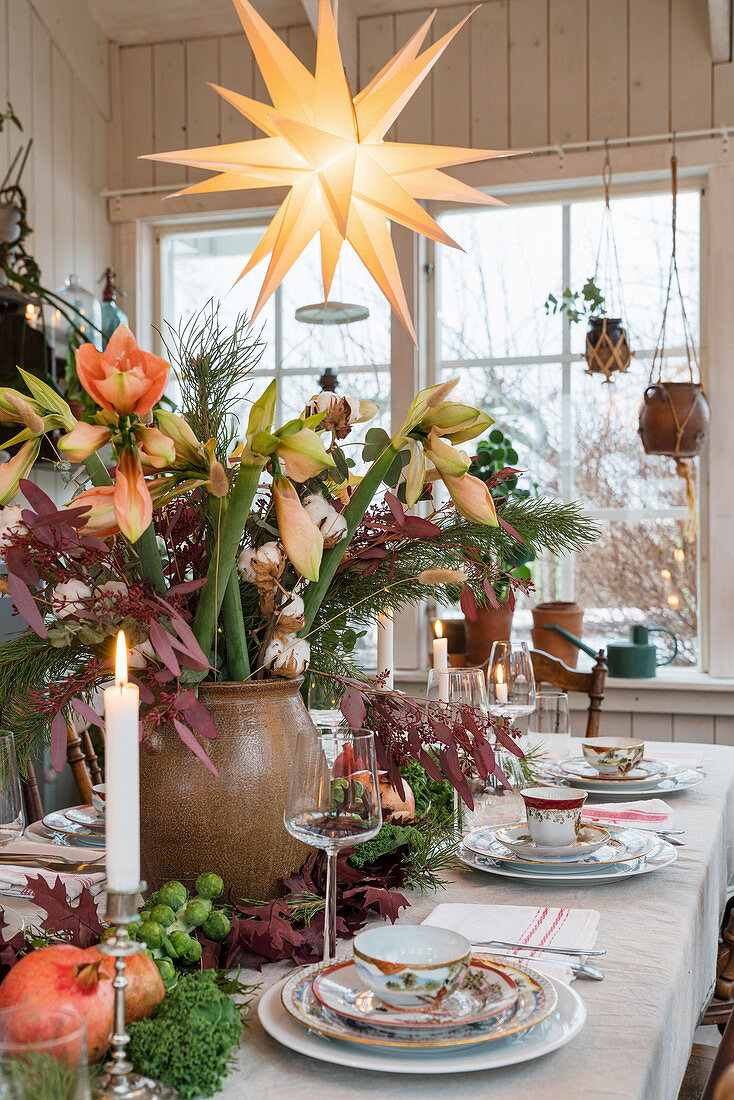 Lavish table centrepiece of amaryllis and leaves on set dinner table