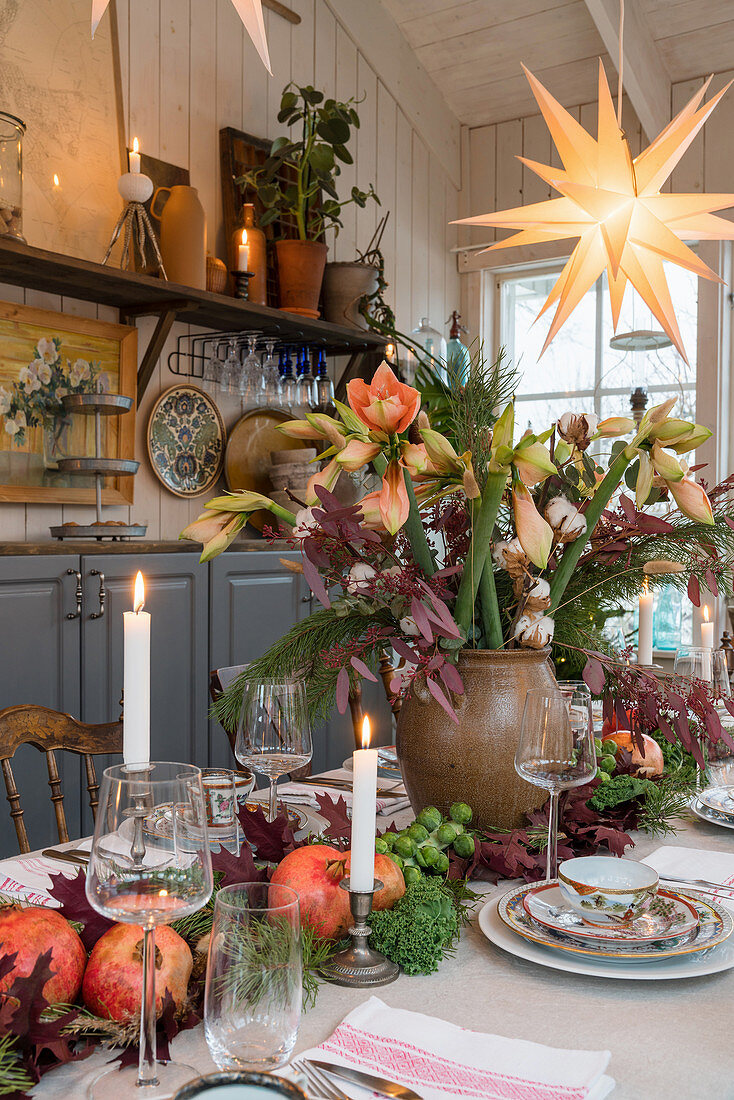 Üppiges Centerpiece mit Amaryllis und Laub auf gedecktem Tisch