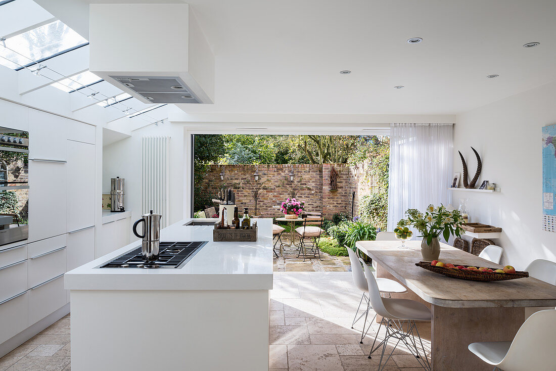Open-plan kitchen with access to garden in white, modern interior