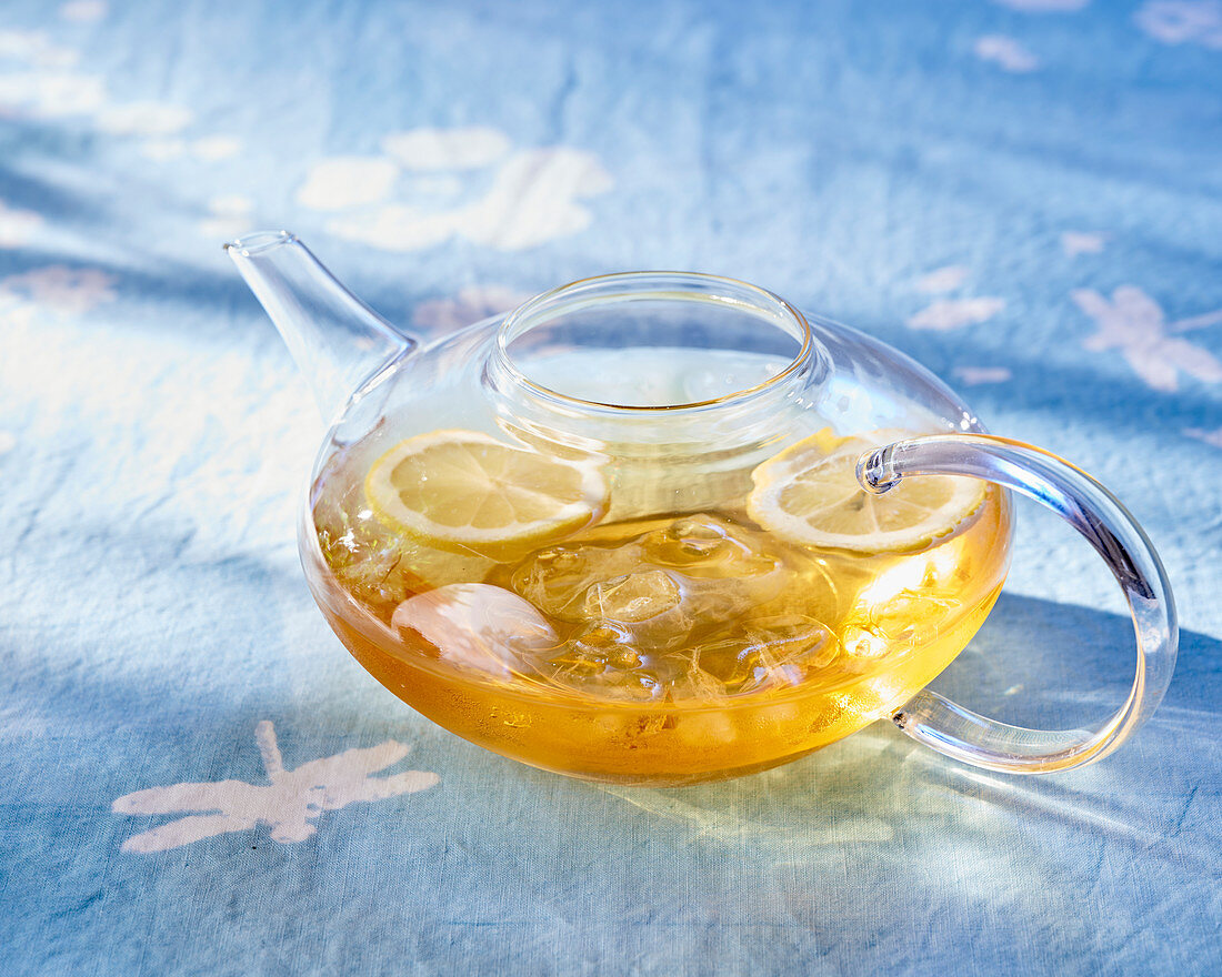 Iced tea with lemon in a glass teapot