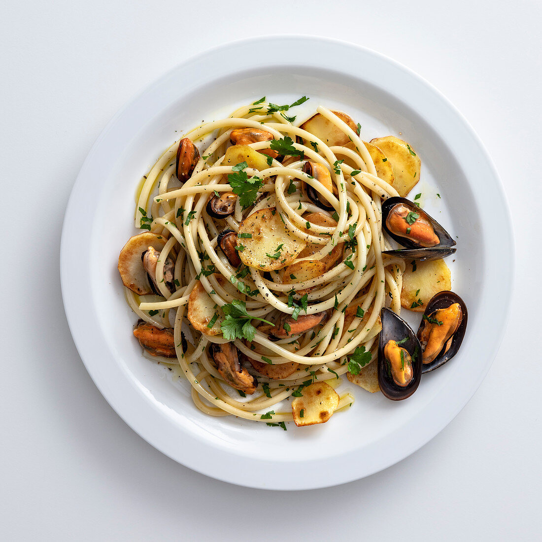 Spaghetti with fried potatoes, fried garlic and mussels