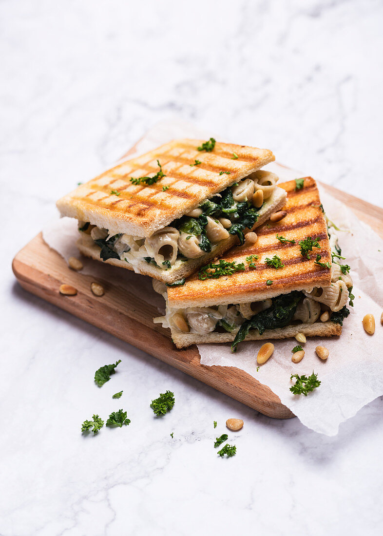 A toasted sandwich with vegan mac and cheese, spinach and pine nuts