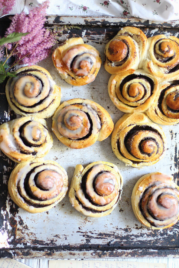 Glazed poppyseed buns on a backing tray