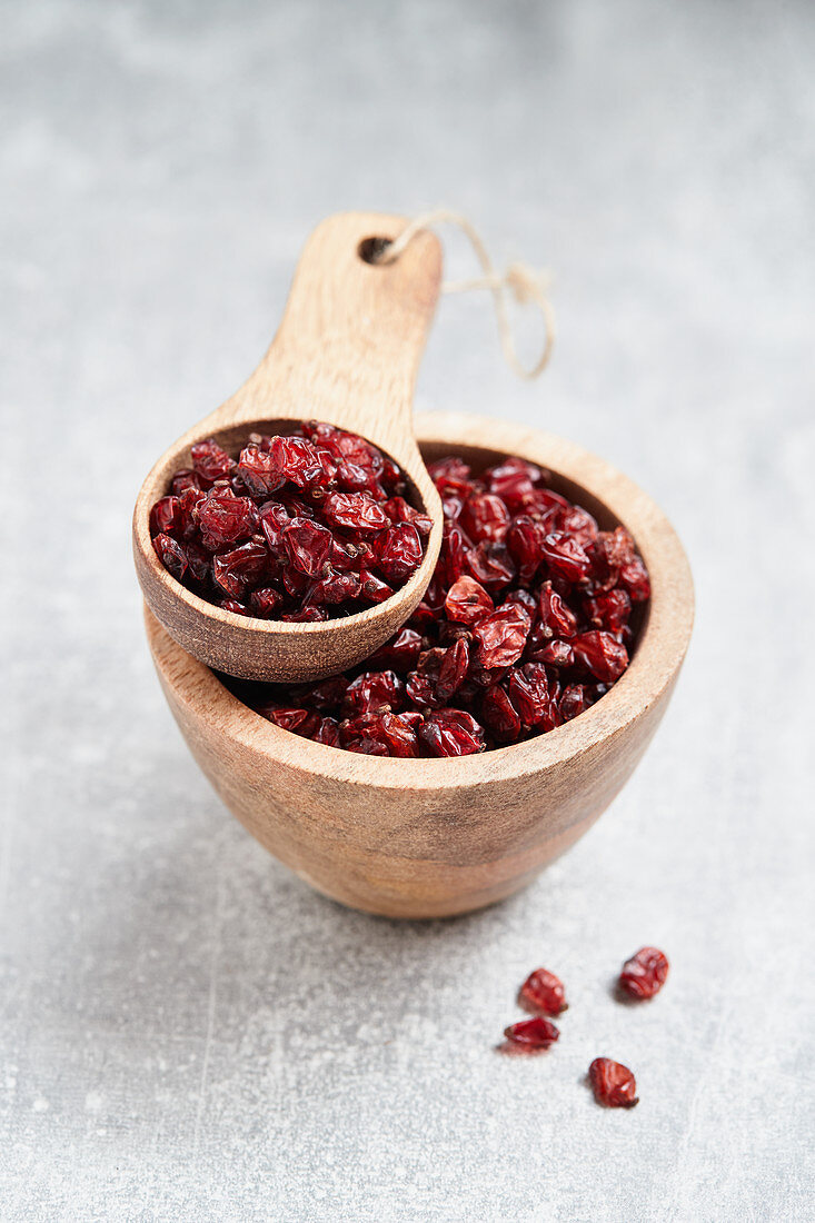 Dried barberries in a wooden bowl and a wooden scoop