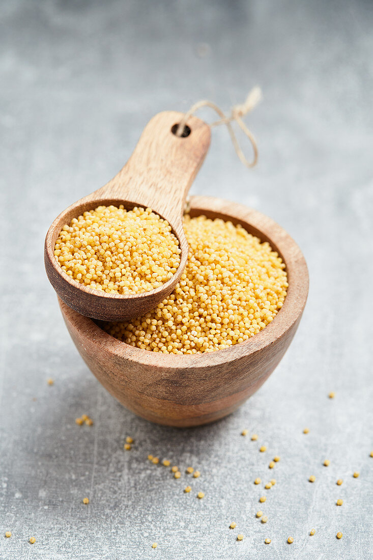 Millet in a wooden bowl and a wooden scoop