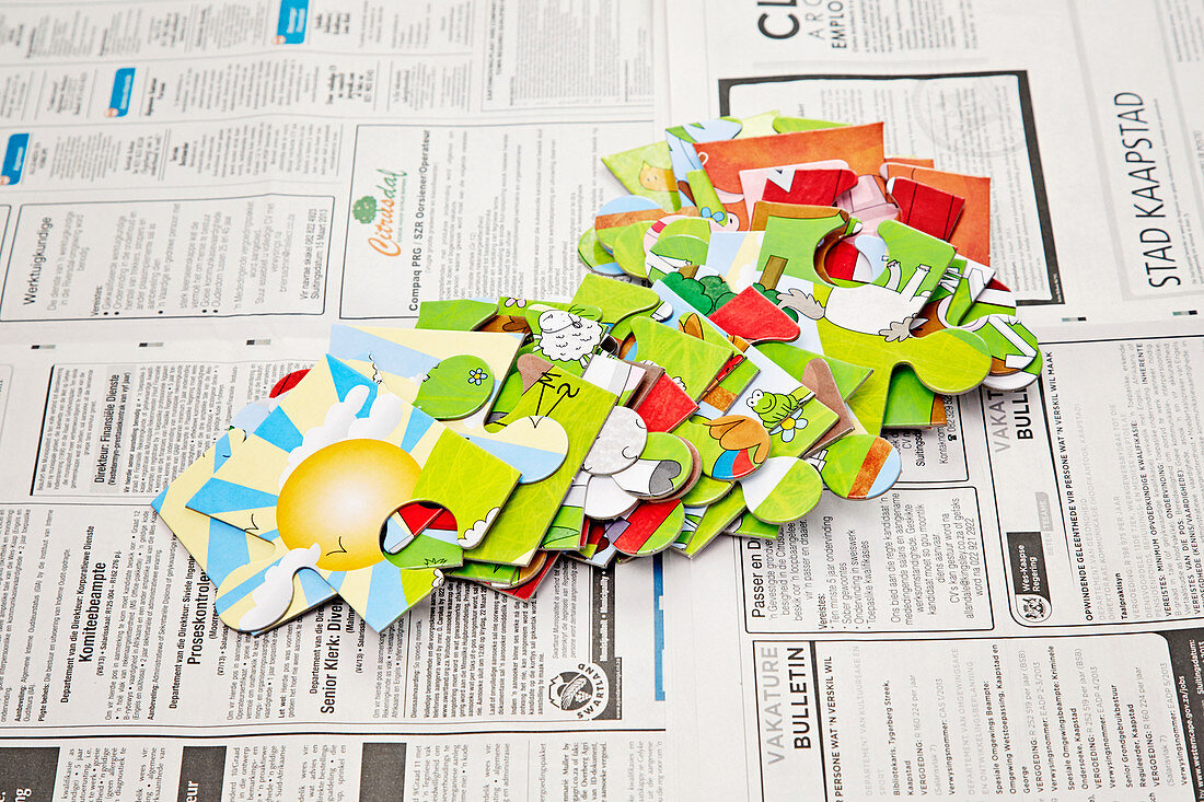 Large jigsaw pieces spread out on newspaper