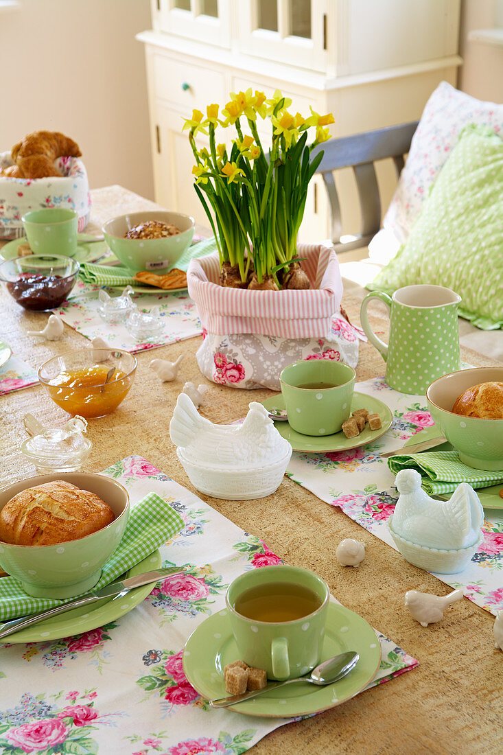 Romantischer Ostertisch mit grünem Geschirr und geblümten Tischsets