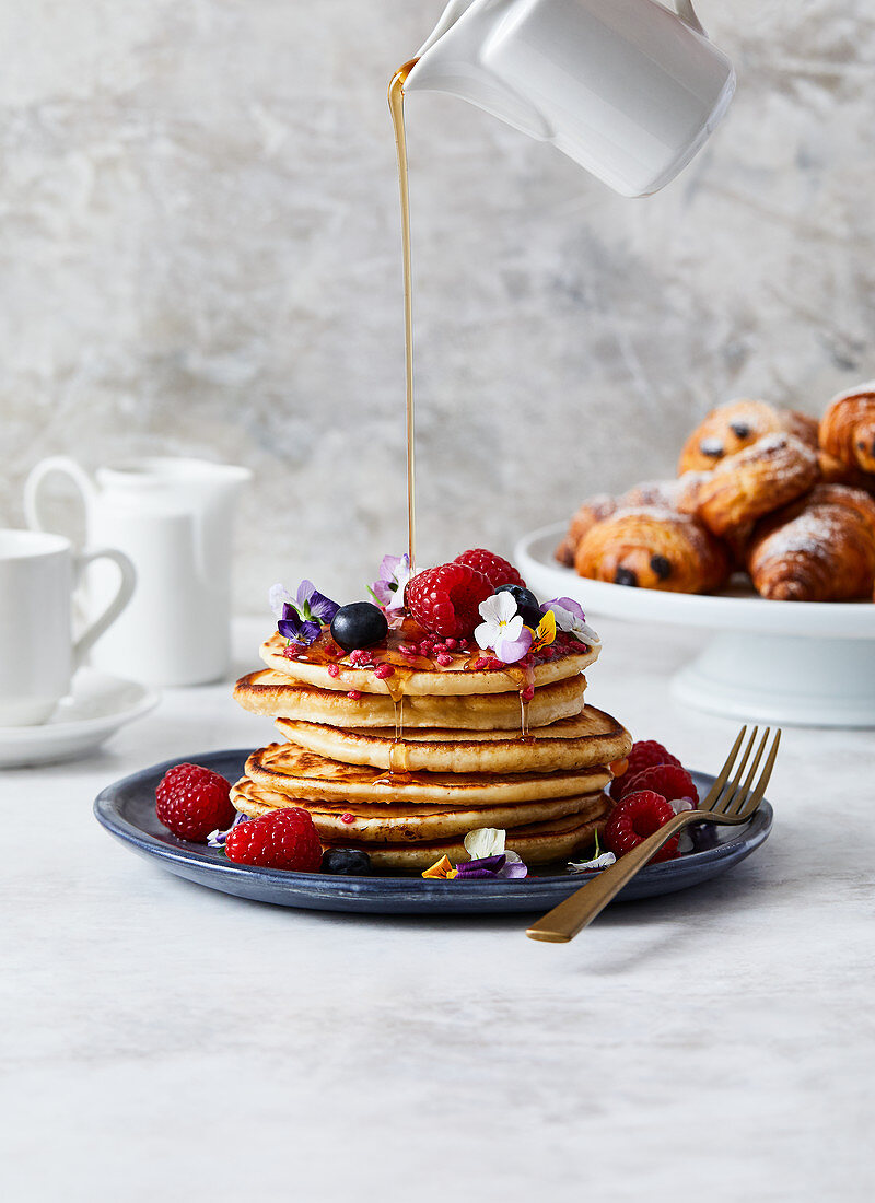 A stack of pancakes served with summer berries and syrup