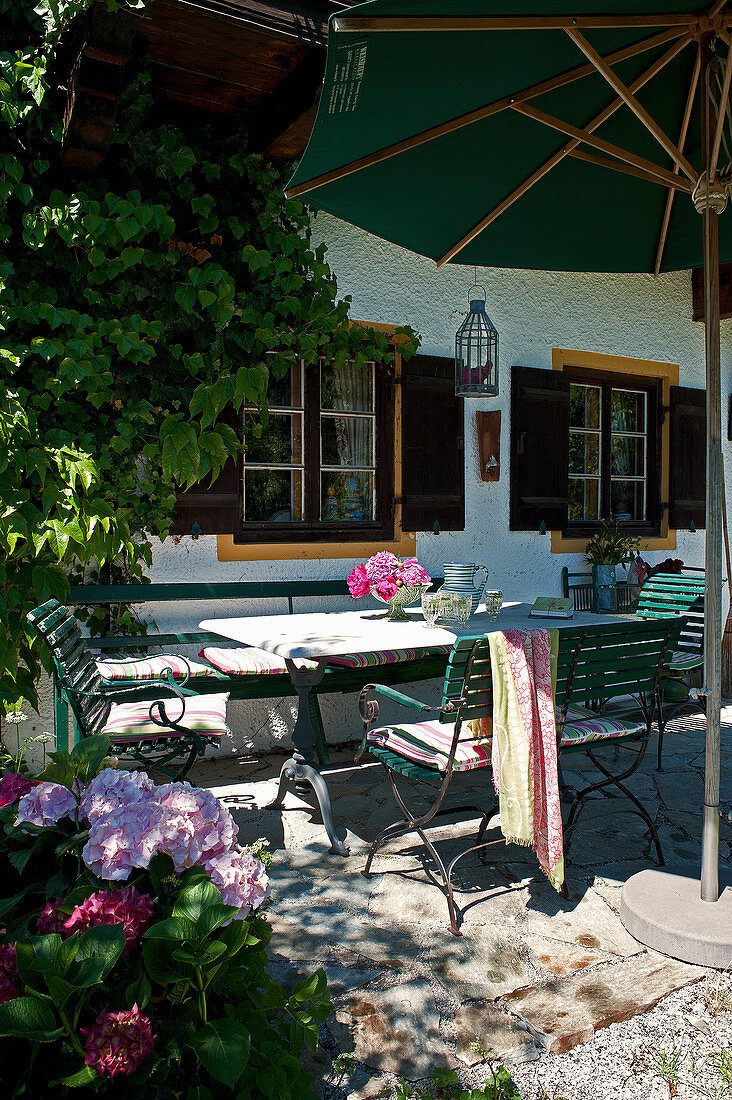 Garden table and chairs below parasol on terrace