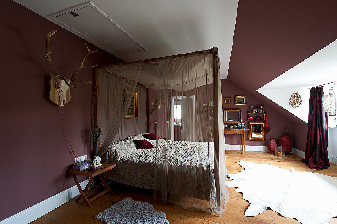 Four-poster bed in bedroom with aubergine walls