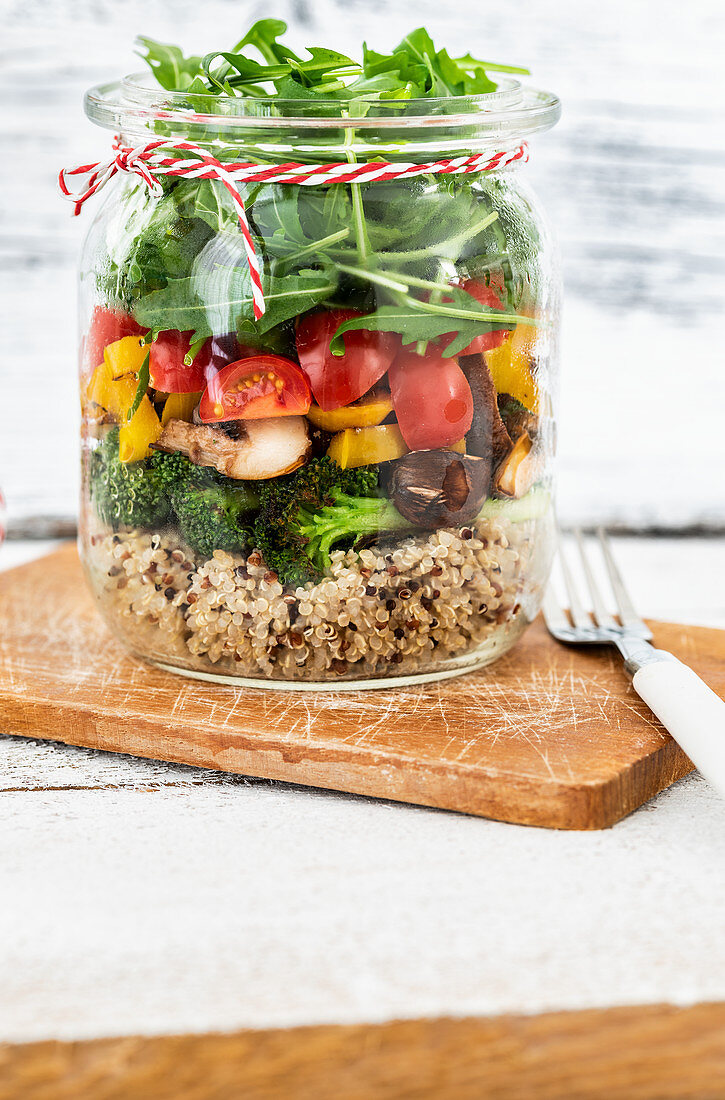 Salad in a jar with quinoa, mushrooms, broccoli, pepper, tomatoes and rocket