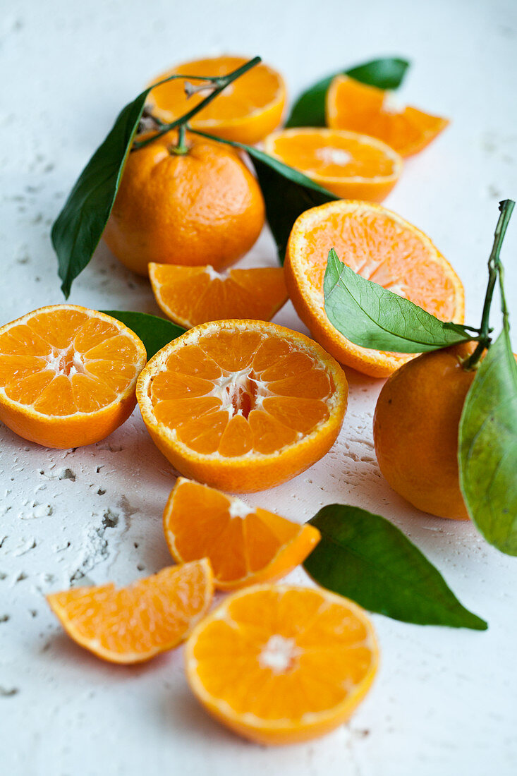 Ganze und halbierte Orangen mit Blättern