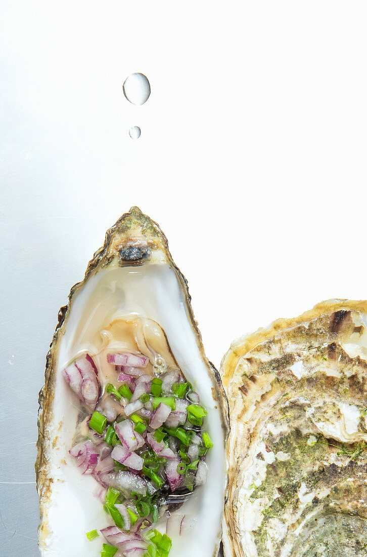 An open oyster with chives and onions