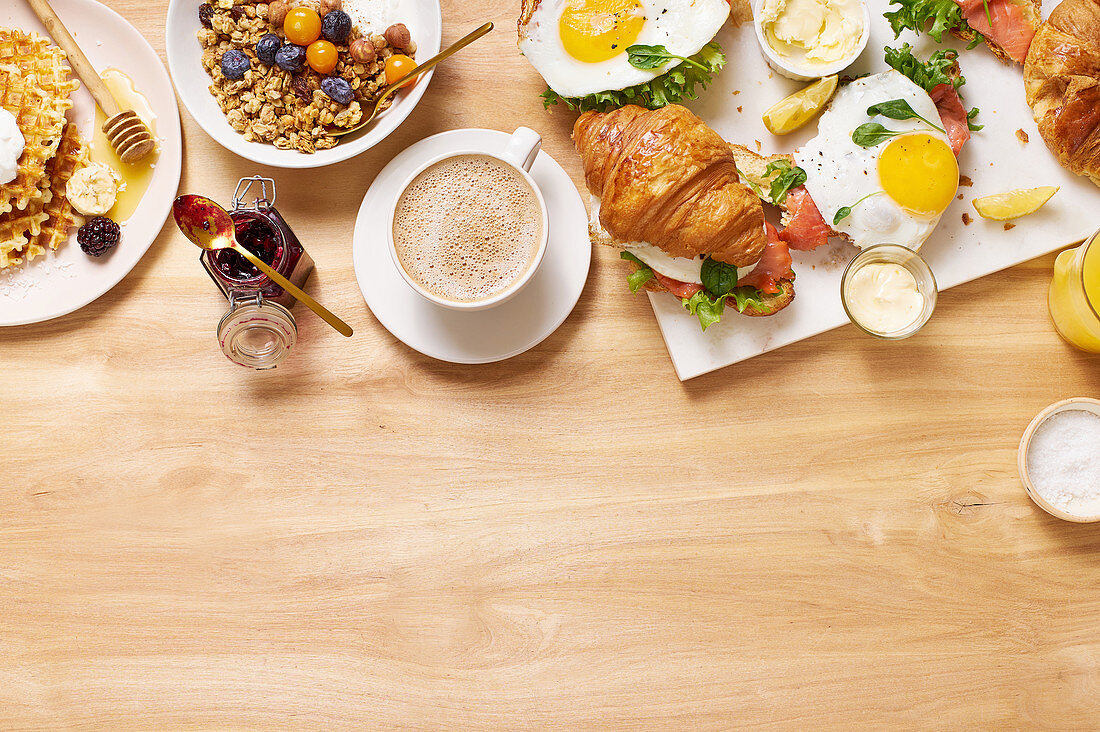 Gesundes Sonntagsfrühstück mit Croissants, Waffeln, Müsli und Sandwiches