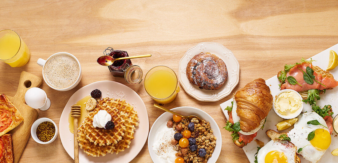 Healthy sunday breakfast with croissants, waffles, granola and sandwiches