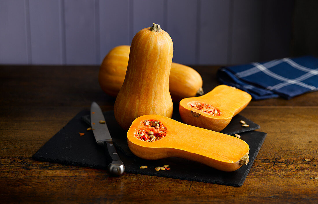 Butternut squash, whole and halved, on a chopping board