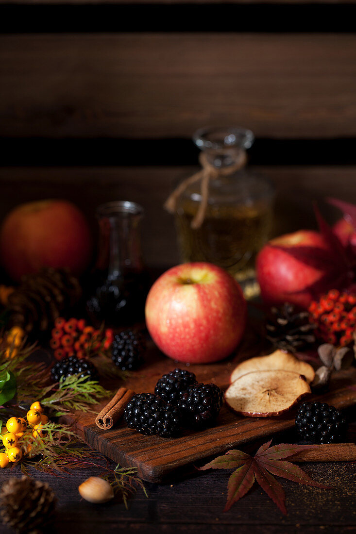 Äpfel und Brombeeren auf Holzbrett mit Herbstlaub