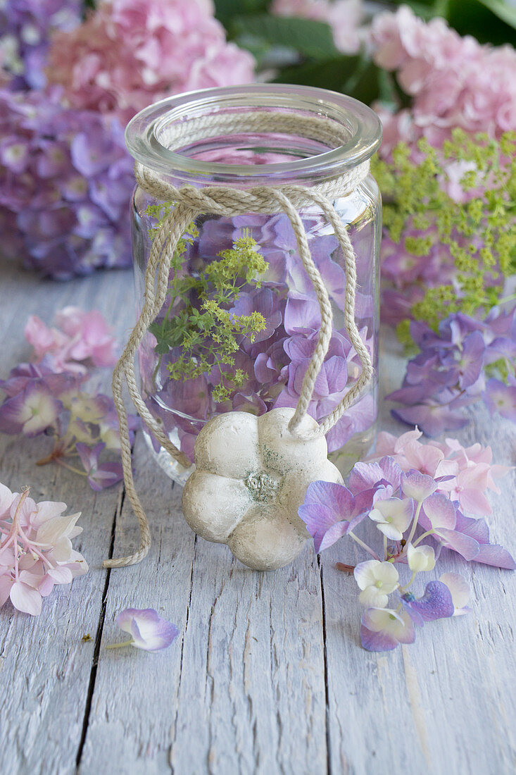 Hydrangea flowers, lady's mantle and plaster flower around preserving jar