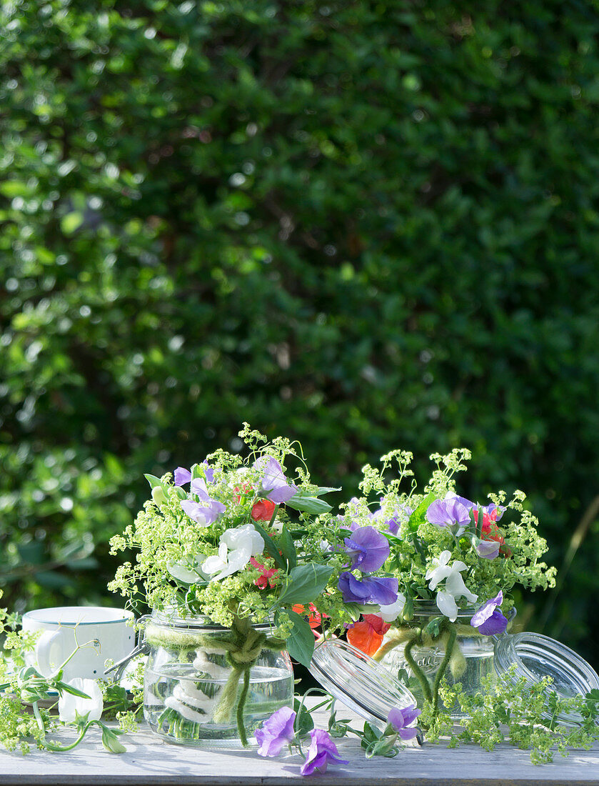 Bouquets of sweet peas and lady's mantle in mason jars