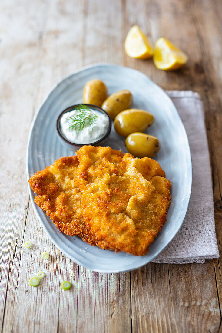 Panierte Schnitzel mit jungen Kartoffeln und Kräuterdip