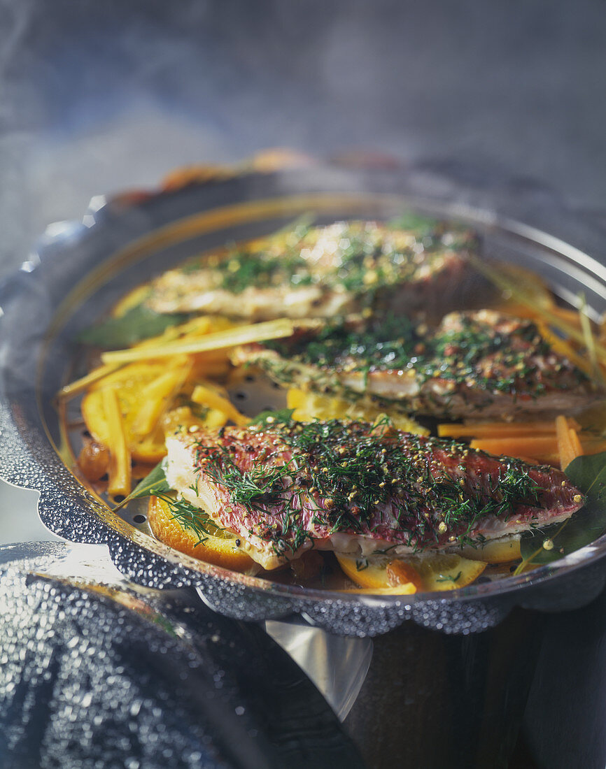 Steamed red mullet with a herb crust on a medley of vegetables and oranges