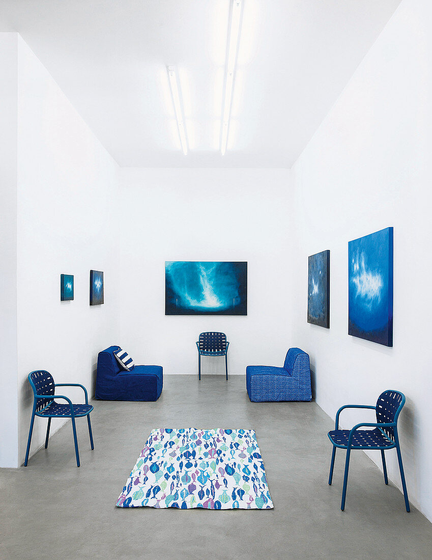 Chairs with woven seats and backs and modular outdoor armchairs in shades of blue in exhibition space