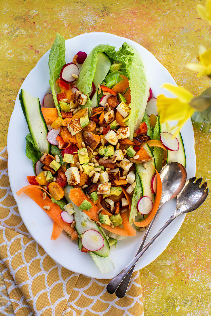Spring salad with avocado, carrots, courgettes, radishes and pine nuts