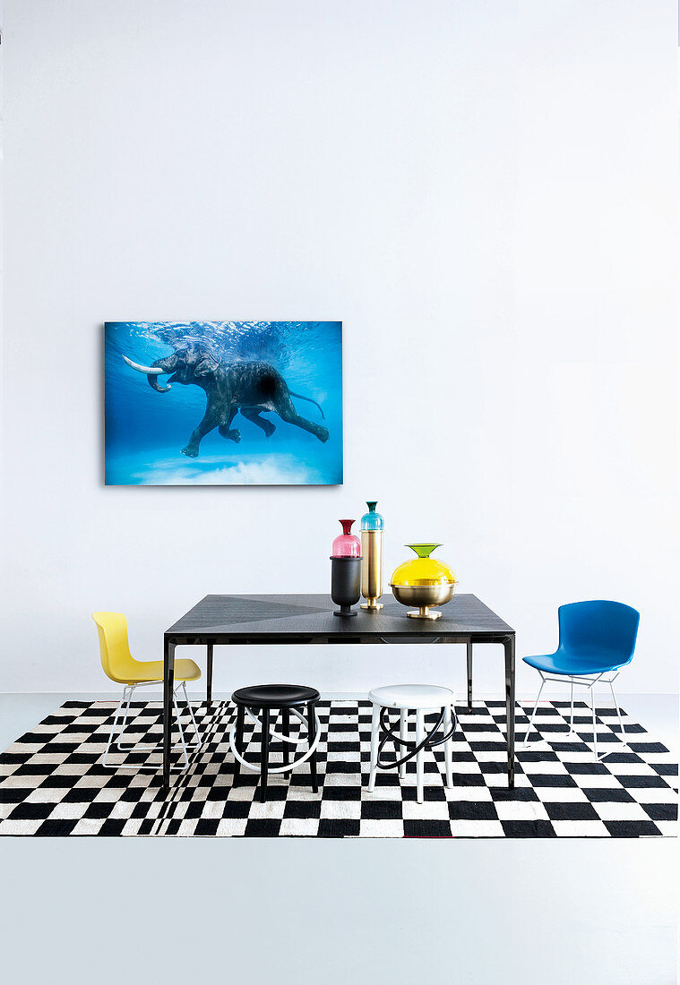 Schwarzer Tisch mit Schalenstühlen und Hockern auf schwarz-weißem Teppich