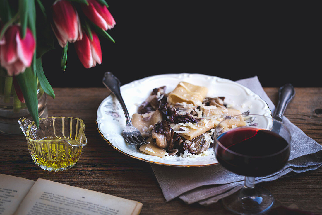 Pasta with radicchio, panceta and Parmesan served on a plate, on a rustic wooden table