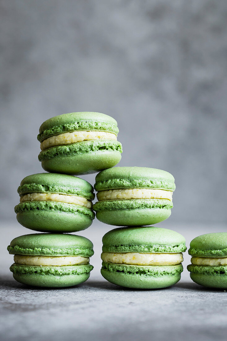 Matcha-Macarons mit Mangobuttercreme vor grauem Hintergrund