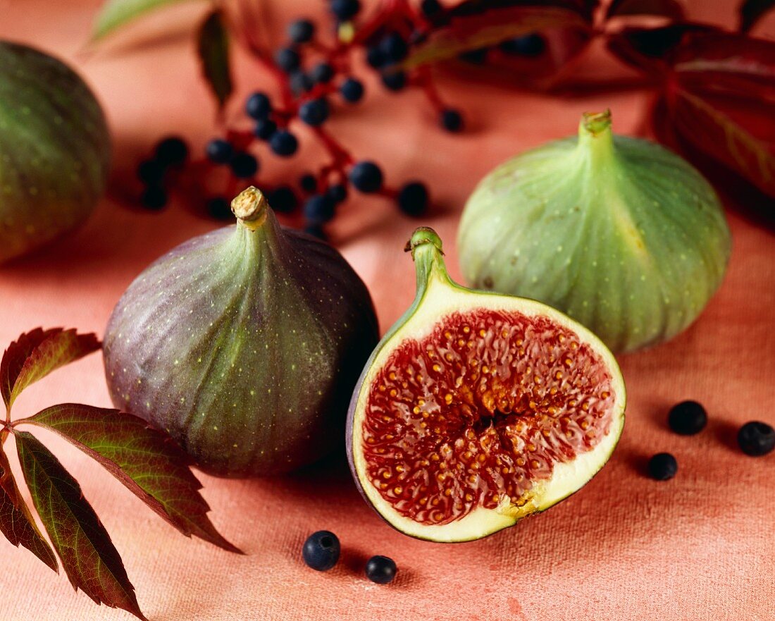 Figs, one cut open, on pink fabric background