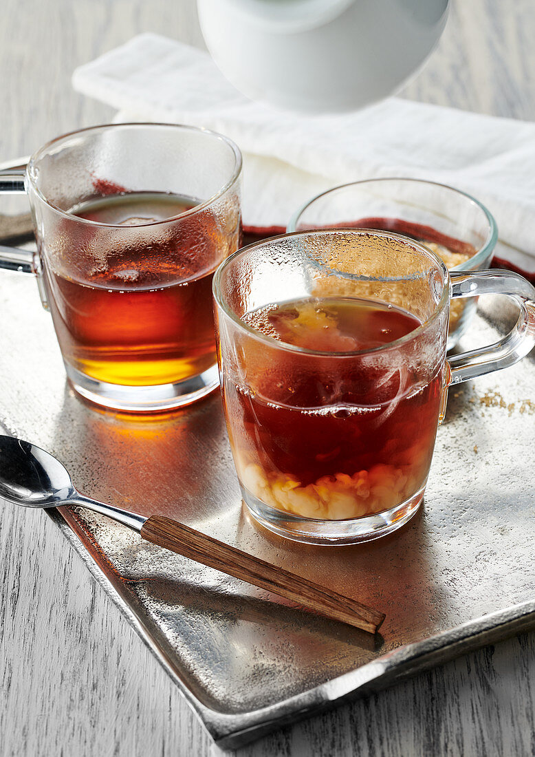 Earl Grey tea with milk in tea glasses on a silver tray