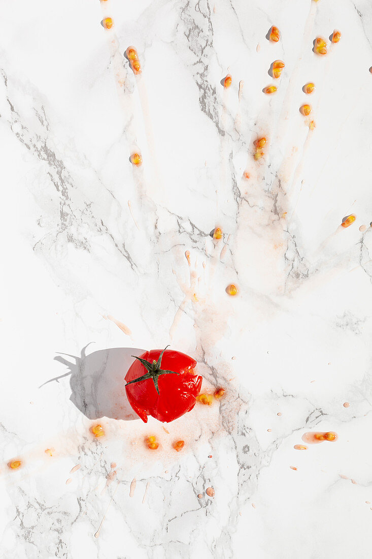 Eine aufgeplatzte Tomate auf Marmoruntergrund
