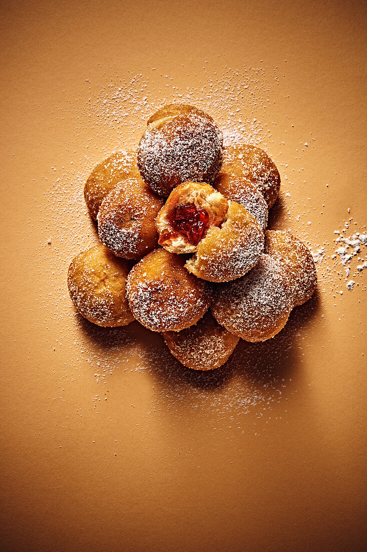 A stack of mini jam doughnuts with icing sugar