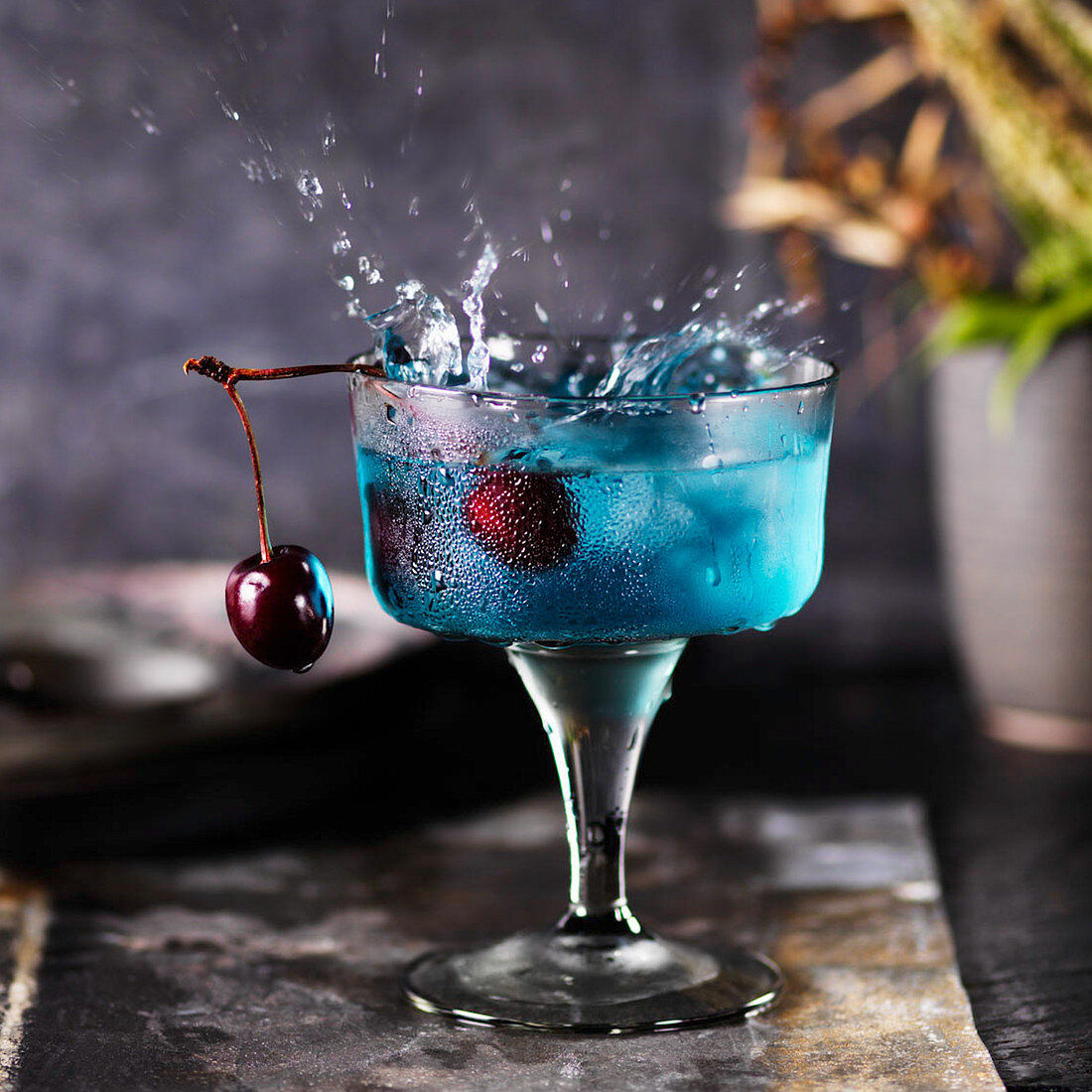 Spritzender Cocktail mit Blue Curacao und Kirsche