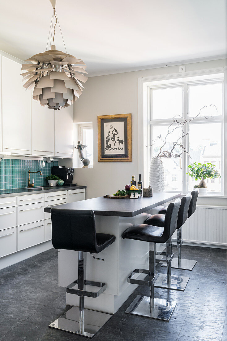 Black barstools at counter and designer lampshade in modern kitchen